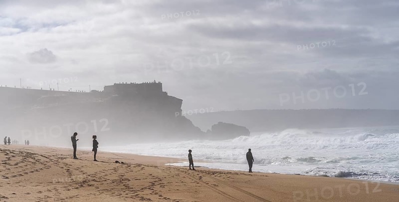 Tourists watch the waves of the Atlantic on the rocky plateau of Sito, also known as Forte São Miguel, a surfing paradise with monster waves in the months of November to February, Nazaré, Portugal