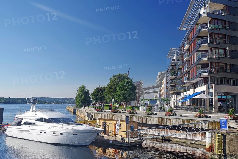 White yacht moored at dock next to modern buildings and clear blue sky, Oslo Fjord, Aker Brygge, Oslo, Norway