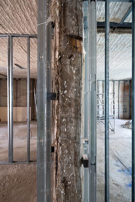 Image of a construction site featuring exposed metal framing, a wooden beam, and a rough concrete floor, capturing the essence of development in progress