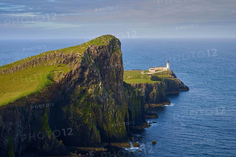 Close-up of a lighthouse on a green cliff surrounded by blue sea, Neist Point Lighthouse, Waterstein, Isle of Skye, Scotland, United Kingdom, Great Britain