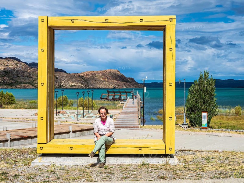 Woman sitting in an oversized frame, art object, pier at Puerto Ingeniero Ibanez, lake Lago General Carrera, Patagonia, Chile