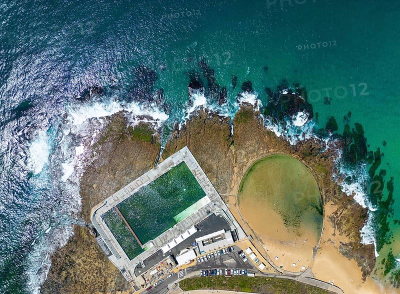 Aerial shot of the ocean pool and surrounding artificial coastline in New South Wales, Australia. The turquoise waters and waves create a stunning seascape