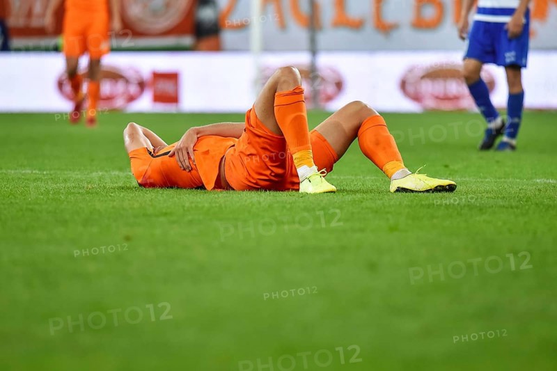 The injured footballer lies on the pitch.
