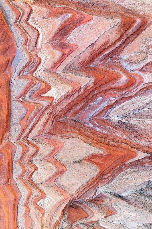 Stunning aerial photograph capturing the intricate sedimentary rock formations by the San Juan River in Utah. The curved layers showcase a natural palette of earth tones