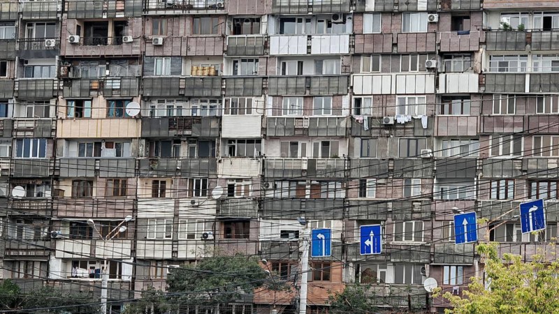 Façade of an old apartment block full of cables and road signs in the foreground, Yerevan, Armenia