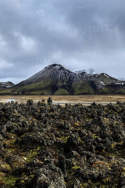Rugged Icelandic Highlands showcase a majestic mountain under dramatic skies, surrounded by volcanic rock formations. Pristine nature in its untouched grandeur