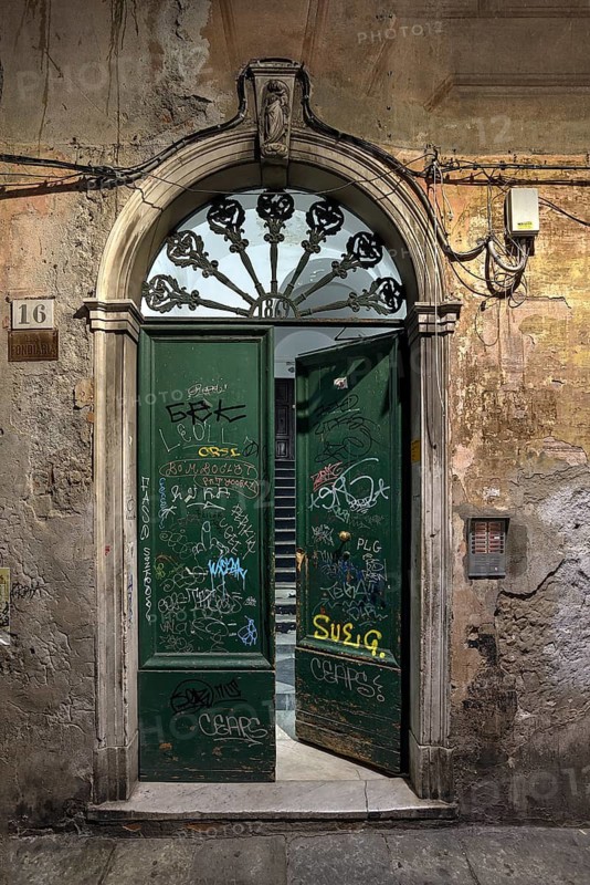 Old front door in an alley in the old town centre smeared with graffiti, Gnua, Italy