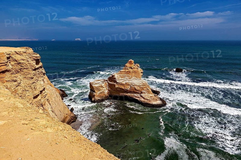Coastal landscape with rocky cliff and calm blue sea under a clear sky, The rocky coast near Paracas in Peru