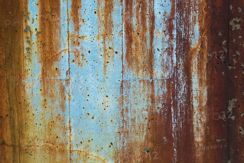 Close-up of long brownish rust streaks, stains and small holes on old light bluish painted concrete wall surface in poor and damaged condition, Quebec, Canada