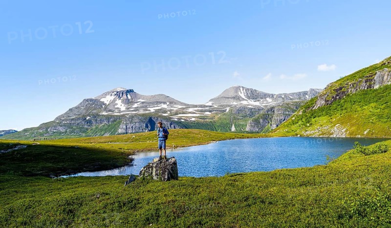Hiker standing on a rock in front of a mountain landscape, small lake in the Flatvaddalen high valley, side valley of Innerdalen, Sunndal, Møre og Romsdal, Vestlandet, Norway