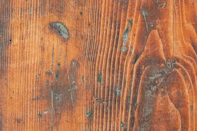 Close-up image of a rustic wooden surface showcasing rich, natural patterns and grooves. The detailed texture and earthy tones highlight the organic beauty of the wood
