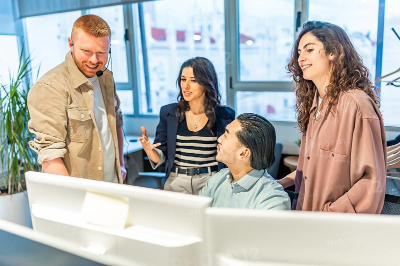 Group of customer service representatives working together on a solution for a client in a modern office