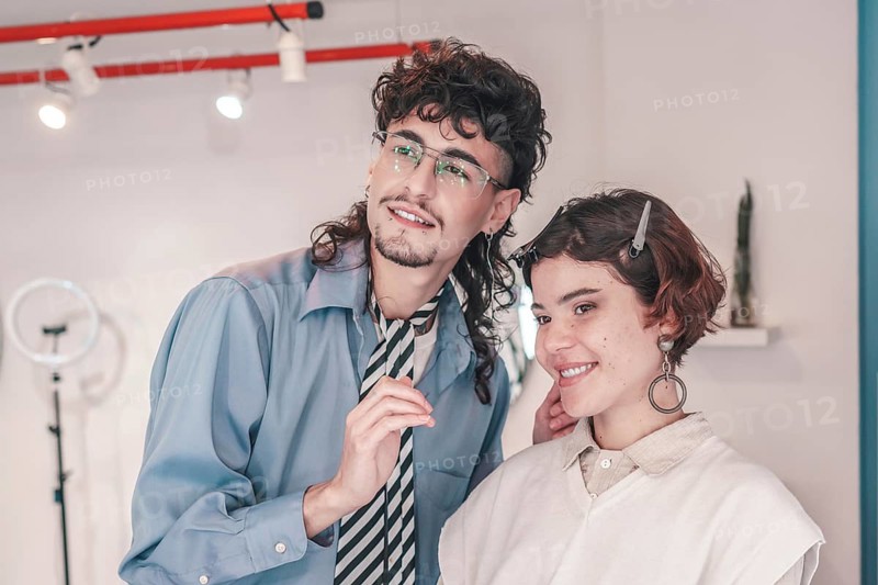In a brightly lit salon, a friendly hairdresser styles a client's hair, showcasing a welcoming environment that embraces diversity and promotes inclusivity