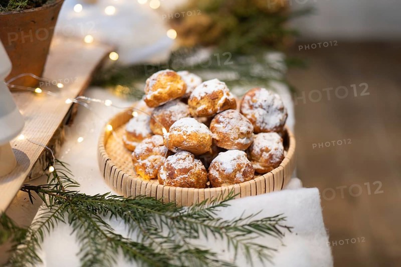 A rustic basket filled with powdered holiday treats, surrounded by festive greenery and warm lights, creating a cozy and inviting seasonal atmosphere