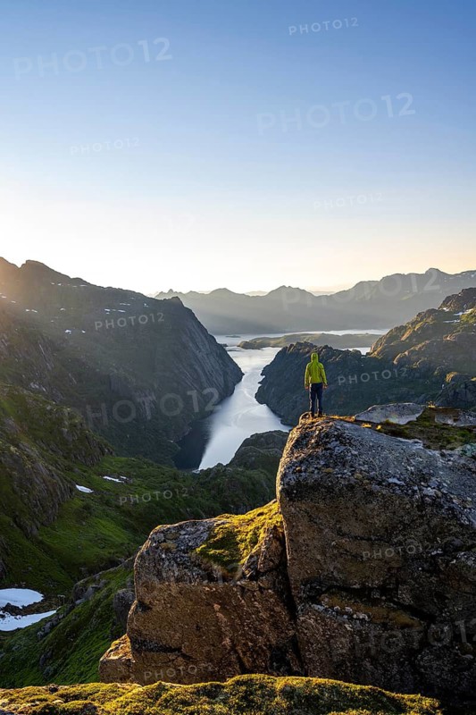 Mountaineer, young man in front of mountain landscape at sunrise, fjord Trollfjord and Raftsund, hike to Trollfjord Hytta, Lofoten, Nordland, Norway