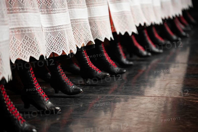 Detail of dancer's legs with black shoe and red laces
