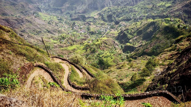 Curvy hiking trail, serpentines lead through a green landscape into a deep valley with surrounding mountains, hiking from Cova Crater through Paul Valley, Ribeira do Paul to Vila das Pombas, Santo Antao, Cabo Verde, Cape Verde, Cape Verde