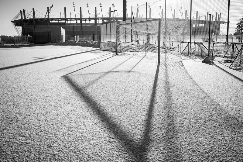 Frozen football pitch covered by snow and stadium in the background
