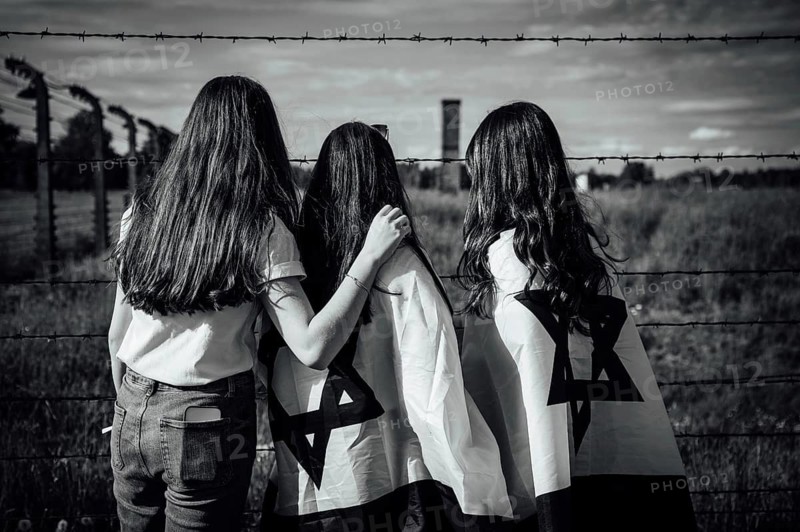 Jewish girls with Israeli flags by the fence of the concentration camp