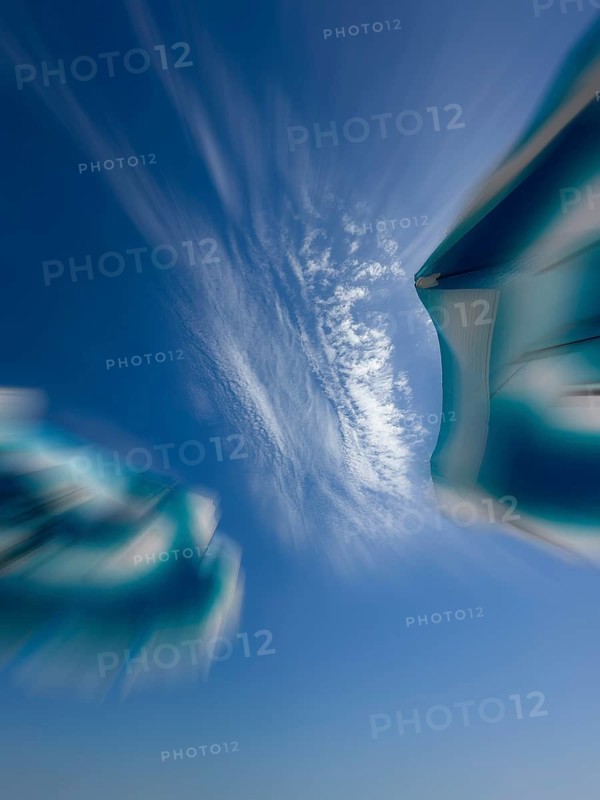 Parasols in front of a blue sky with clouds, zoom effect