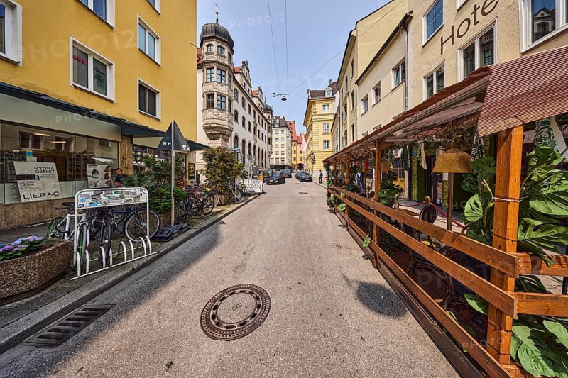 Outdoor area of a restaurant, general architecture, buildings, residential buildings and commercial buildings, hotel, street, pale blue sky, cumulus clouds, cirrostratus clouds, slightly diffused and sunny light, Ledererstraße, Munich, state capital, district-free city, Bavaria, Germany