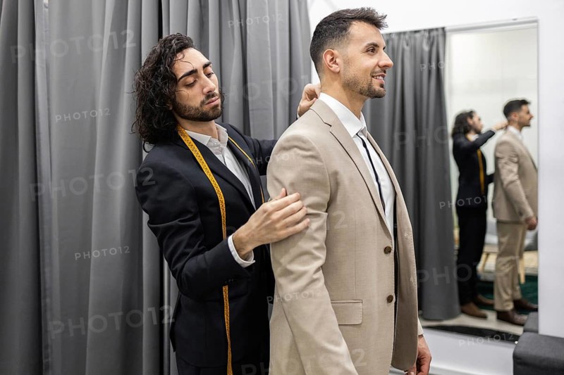 A professional tailor adjusts a client suit, ensuring perfect fit. The scene captures the precision involved in tailoring in a suit store