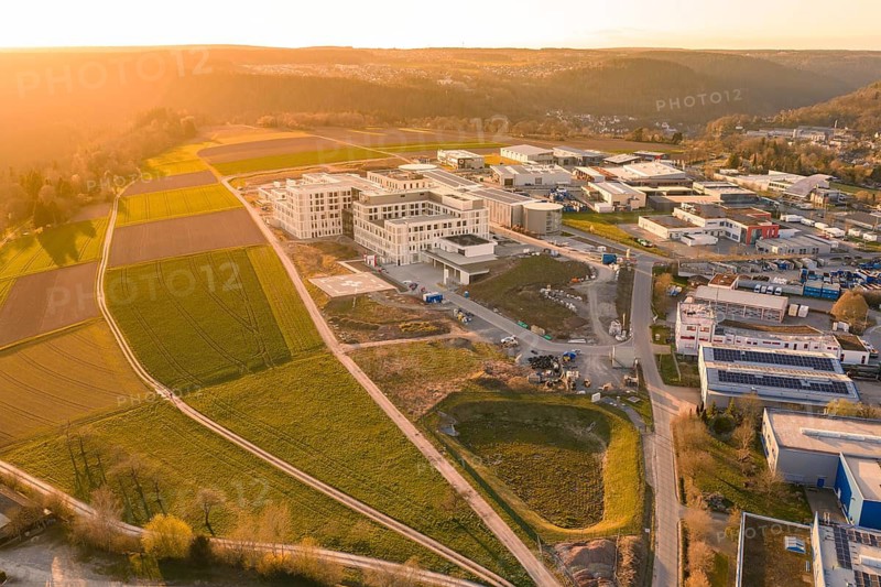 Aerial view of an industrial area with green fields and buildings in a warm sunset, new hospital at the Verbund Südwest Clinic, Calw, Germany
