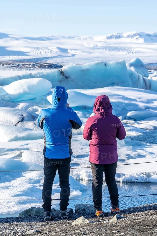 A couple of tourists looking at floating icebergs in Jokulsarlon glacier lagoon in Iceland