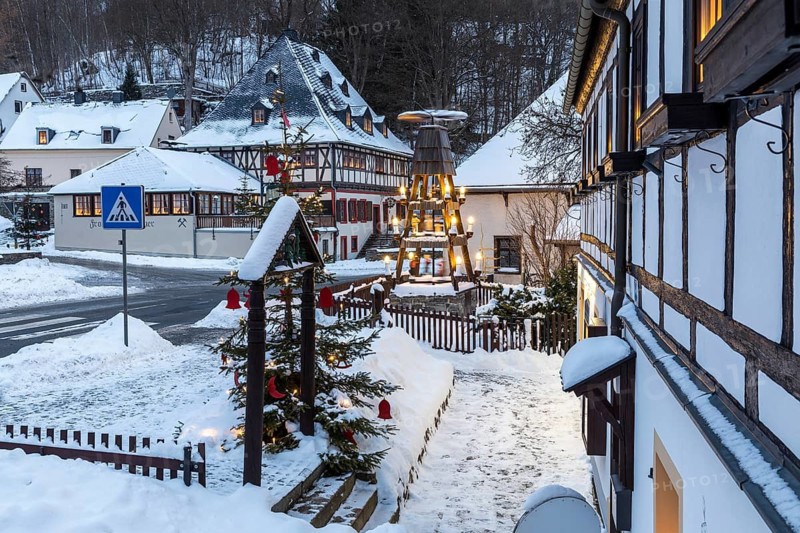 Twilight view of Hammerherrenhaus and village pyramid in snow, Frohnauer Hammer, Annaberg-Buchholz, Ore Mountains, Saxony, Germany