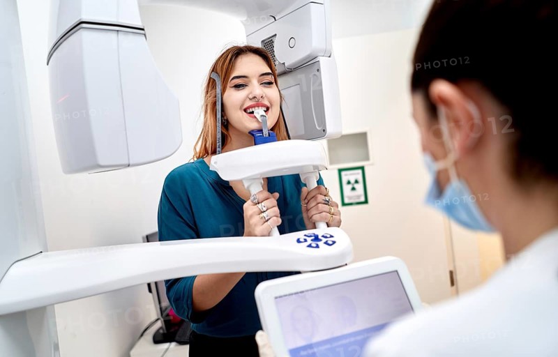 A young woman undergoes a dental imaging procedure in a modern clinic, aided by a skilled dental professional, showcasing advanced oral healthcare technology