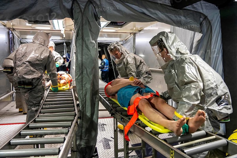 Decontamination of injured persons after an assumed accident involving hazardous substances, fire brigade and aid organisations practise setting up and operating a decontamination station, injured persons are sighted and then washed in a special shower tent to remove possible hazardous substances and chemicals in order to avoid further injuries, the emergency services wear special, ventilated protective suits, large-scale exercise by the Essen fire brigade