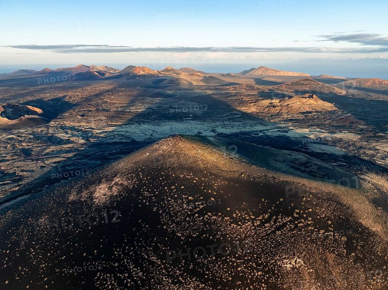 Picturesque volcanic landscape with volcanic craters and lava fields in morning light, Montaña Negra volcano and Volcán de Las Nueces, Parque Natural de Los Volcanes, aerial view, Lanzarote, Canary Islands, Spain