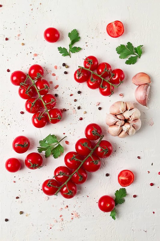 Branch with mini cherry tomatoes, with spices and herbs, garlic, food background, top view, on a white background