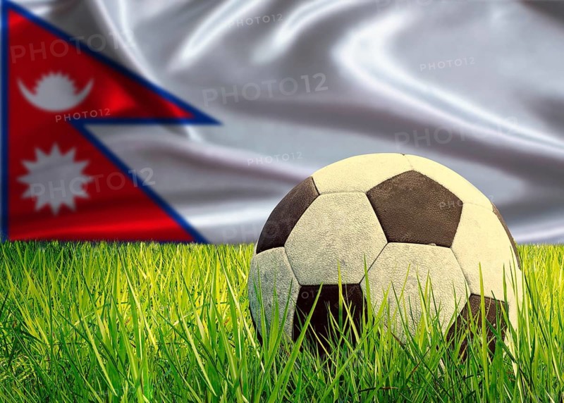Soccer ball on the grass with Nepal flag in the background. Soccer ball on pitch against Nepalese flag in the background