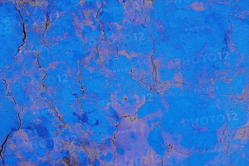 Close-up of a cracked blue textured concrete surface, showcasing intricate patterns and rough textures. The surface details highlight natural wear, creating a captivating abstract background