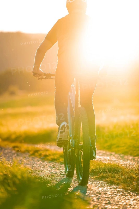 Person riding in the evening sun on a dusty path across a field, e-bike, forest bike, Calw, district of Calw, Black Forest, Germany