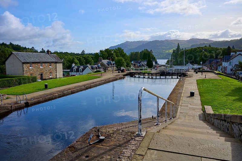 A paved canal area with views of buildings and mountains under clear skies, Caledonian Canal, Fort Augustus, Loch Ness, Scotland, United Kingdom, Great Britain