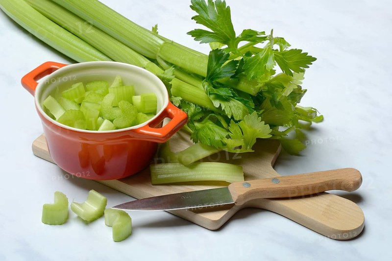 Celery stalks, pieces in pots with kitchen knife