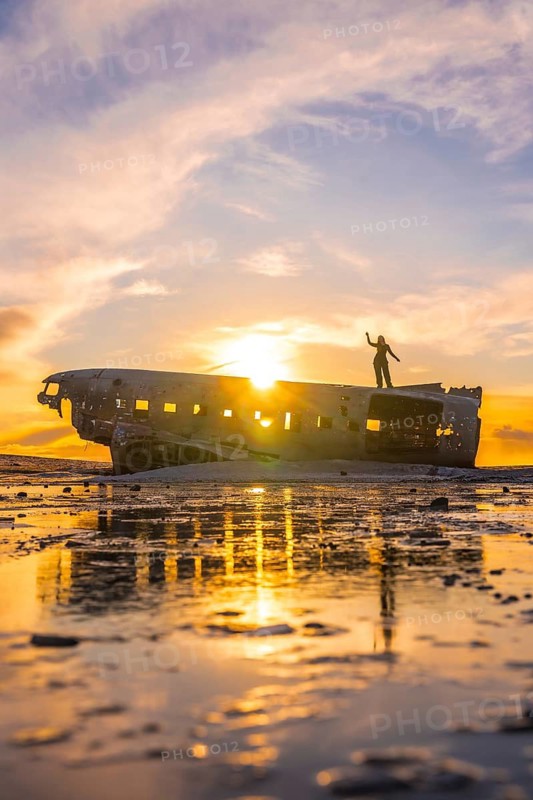 Woman on top of the Solheimasandur plane at a winter sunrise in Iceland