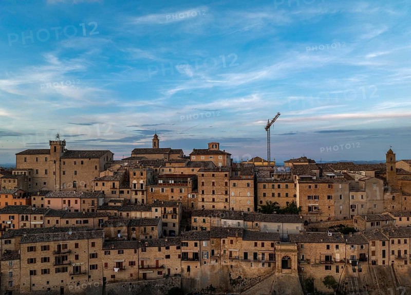 Capture of Treia's historic skyline featuring ancient architecture under a blue evening sky. The buildings showcase Italy's rich heritage and timeless charm