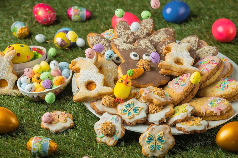 Decorated Easter cookies on a plate with colorful eggs in the grass
