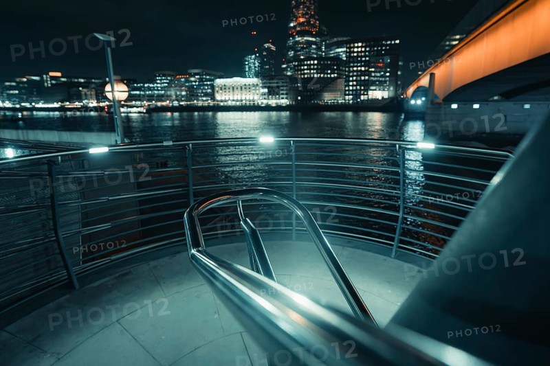 Illuminated stair railing on the riverbank in a modern city at night, New Year's Eve London, United Kingdom