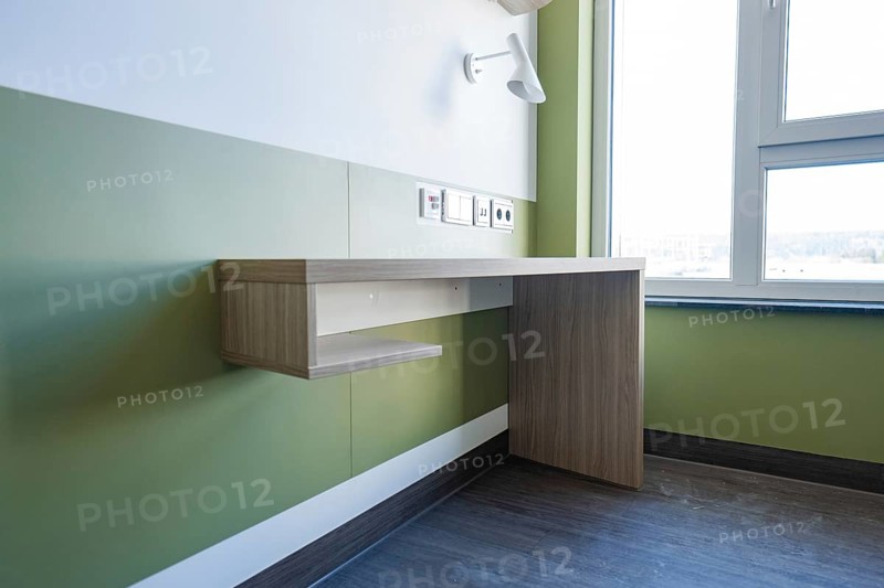 Corner desk with power outlets in front of a green wall and a window, patient room optional service in the new hospital, Calw, Germany