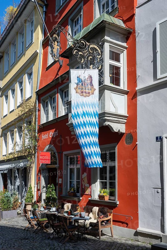 Picturesque old town alleyway with outdoor restaurants above a Bavarian state flag in the old town of Lindau, Bavaria, Germany