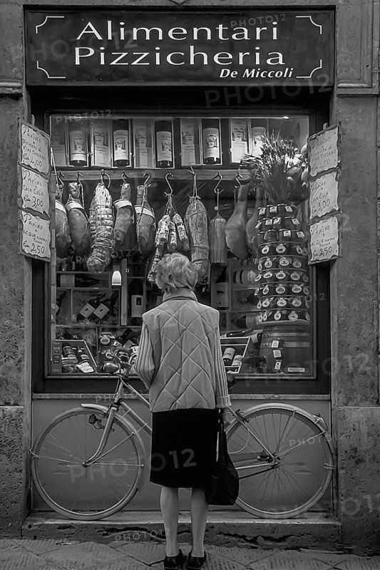 Elderly lady in front of a sausage shop, Siena, Tuscany, Italy