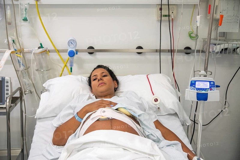 A new mother rests in a hospital bed, surrounded by medical equipment, preparing to give birth. Anticipation and care fill the room, emphasizing the importance of support