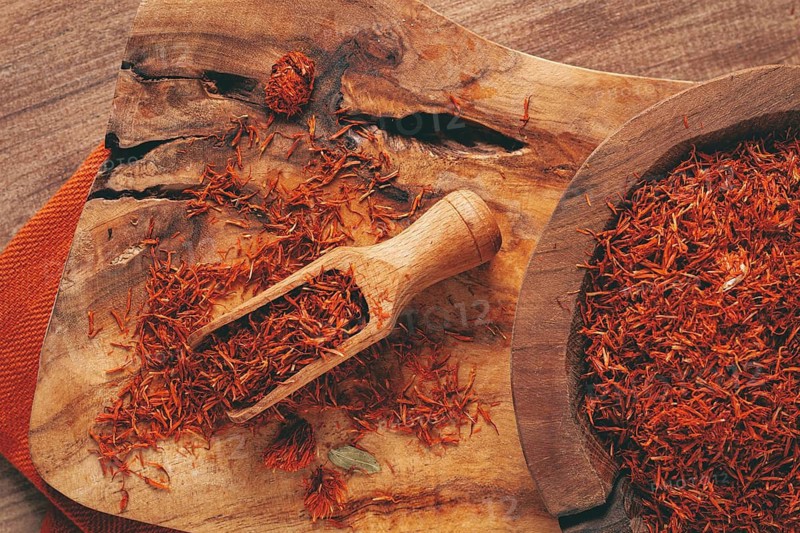 Spice saffron threads, in a wooden bowl, on a wooden table, top view, close-up