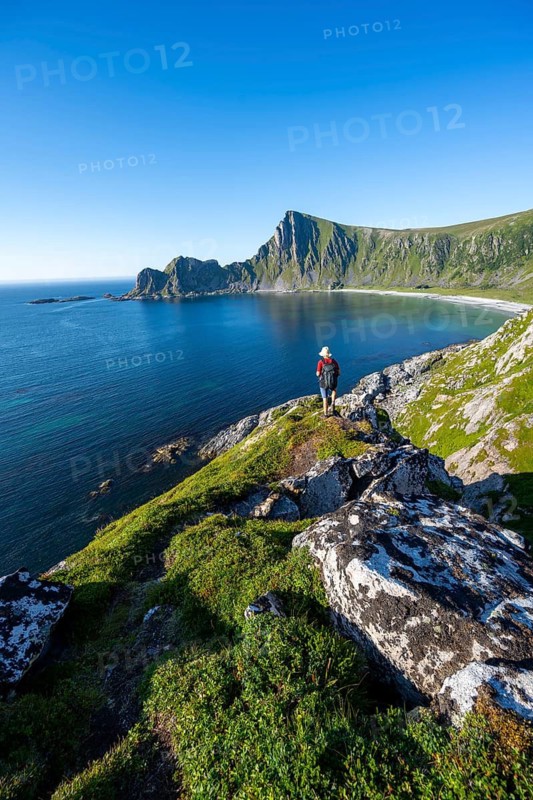Mountaineer with view of coastal landscape, steep coast with peak Måtind, Høyvika beach and sea, hike to the peak of Måtind, Andøya island, Vesterålen, Nordland Norway