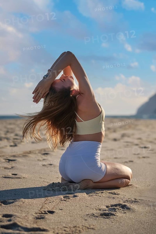 A woman demonstrates Vajrasana Thunderbolt Pose with a deep backbend on a sandy beach during sunset