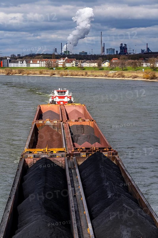 Pushed convoy HGK, Herkules II loaded with coal and ore, on its way to the Krupp Mannesmann steelworks, HKM, in the south of Duisburg, Rhine near Duisburg-Laar, houses on Deichstraße, industrial backdrop of the ThyssenKrupp Steel steelworks in Bruckhausen, blast furnaces, North Rhine-Westphalia, Germany
